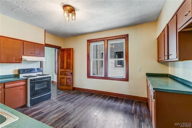 373 Urban St, Buffalo, NY 14211 - kitchen with gas range oven, under cabinet range hood, dark wood-type flooring, a textured ceiling, and dark countertops