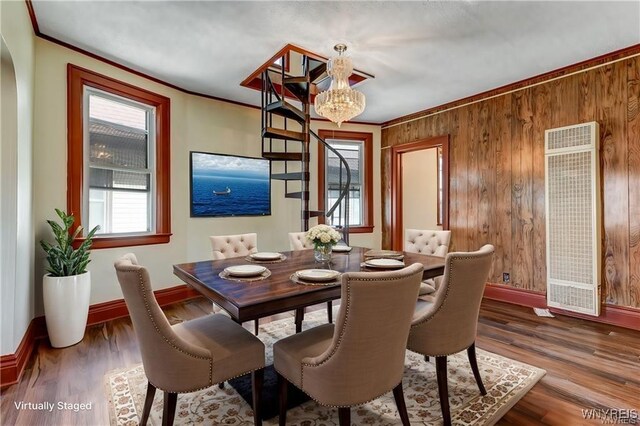 373 Urban St, Buffalo, NY 14211 - dining area with a heating unit, a chandelier, wooden walls, ornamental molding, and wood finished floors
