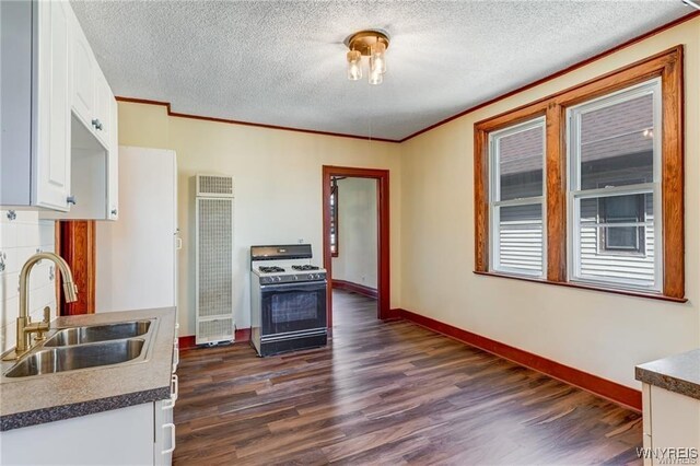 373 Urban St, Buffalo, NY 14211 - kitchen featuring range with gas stovetop, a heating unit, dark wood-style floors, white cabinetry, and a textured ceiling