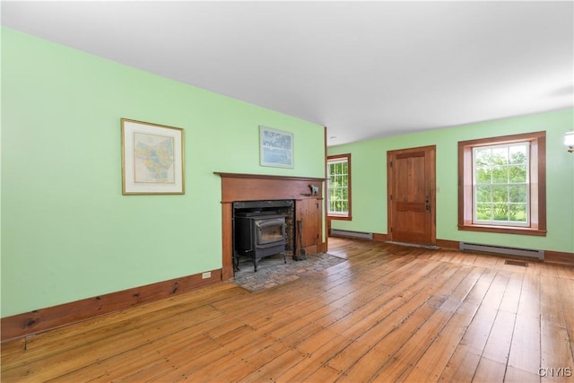 9999 Pierce Rd N, Trenton, NY 13354 - unfurnished living room with a wood stove, a baseboard radiator, and wood-type flooring