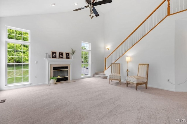 133 Raspberry Ln, Camillus, NY 13031 - carpeted living room featuring high vaulted ceiling, a ceiling fan, stairs, and a fireplace with flush hearth