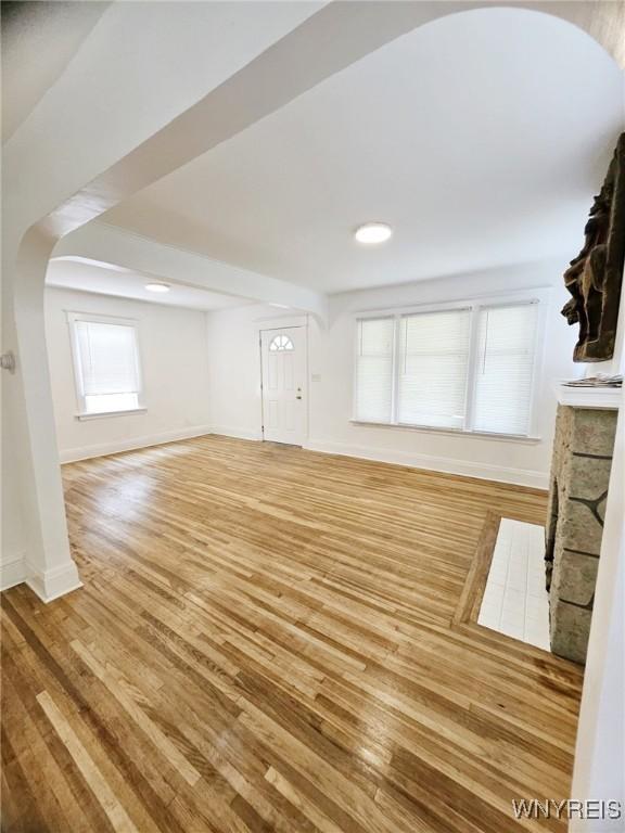 269 Westminster Ave, Buffalo, NY 14215 - unfurnished living room with light wood-style flooring, a fireplace, and arched walkways