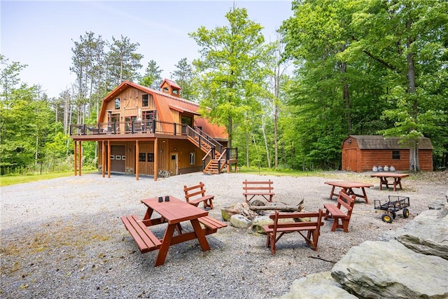 6684 Bishop Rd, Conesus, NY 14435 - rear view of property featuring a fire pit, stairs, a wooden deck, an attached garage, and a storage unit