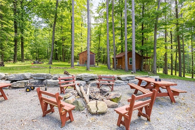 6684 Bishop Rd, Conesus, NY 14435 - view of patio / terrace featuring a fire pit, a storage unit, and a wooded view