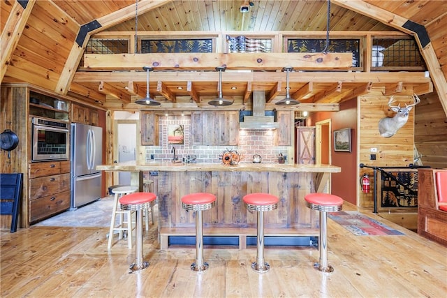 6684 Bishop Rd, Conesus, NY 14435 - kitchen featuring stainless steel appliances, wall chimney exhaust hood, light wood-style flooring, wood walls, and a wood ceiling with exposed beams
