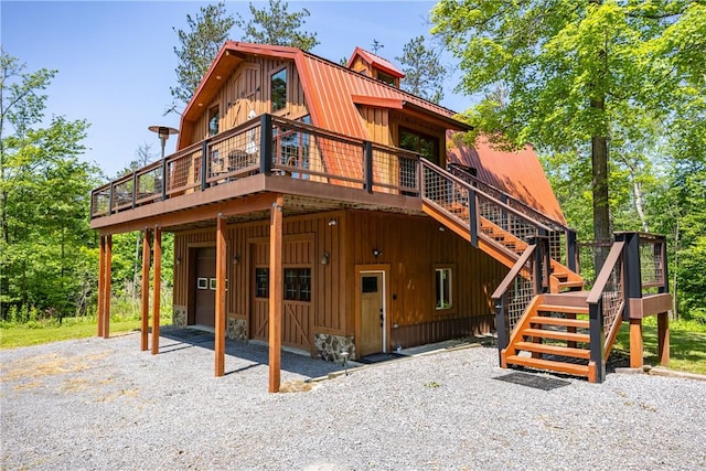 6684 Bishop Rd, Conesus, NY 14435 - rear view of house with stairs, board and batten siding, a deck, a gambrel roof, and driveway