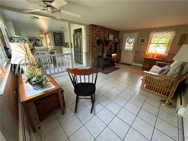 4214 Wilson Burt Rd, Wilson, NY 14172 - living area with a wood stove, ceiling fan, light tile patterned flooring, and baseboard heating