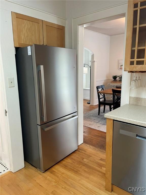 336 Hickok Ave, Syracuse, NY 13206 - kitchen featuring stainless steel appliances, light wood-type flooring, light countertops, glass insert cabinets, and arched walkways