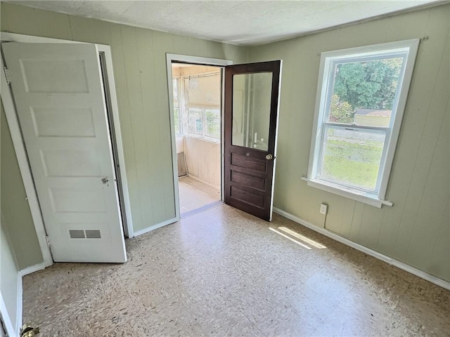 60 Clairmount St, Rochester, NY 14621 - unfurnished bedroom with multiple windows, wood walls, and tile patterned floors