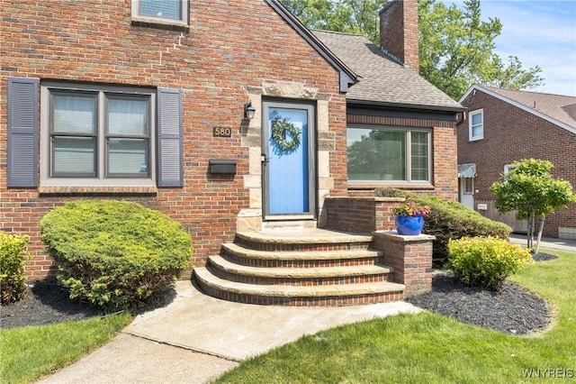 580 Roycroft Blvd, Cheektowaga, NY 14225 - view of exterior entry featuring a chimney, brick siding, and a shingled roof