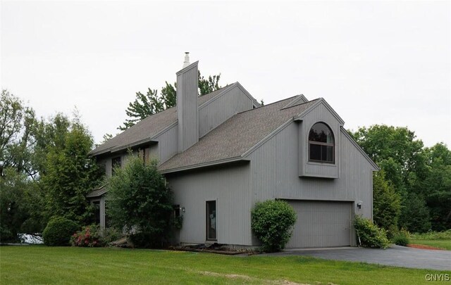 21751 Hewitt Dr, Champion, NY 13619 - view of side of home featuring a yard, a chimney, an attached garage, and driveway