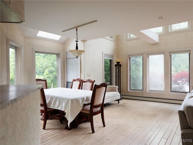 21751 Hewitt Dr, Champion, NY 13619 - dining area featuring a skylight, light wood finished floors, vaulted ceiling, and a baseboard radiator