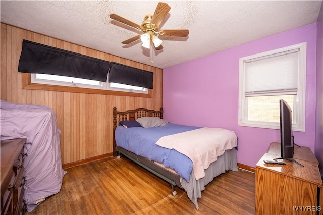 241 Shanley St, Cheektowaga, NY 14206 - bedroom featuring wood finished floors, wooden walls, a textured ceiling, and a ceiling fan