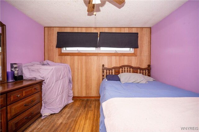 241 Shanley St, Cheektowaga, NY 14206 - bedroom featuring wood finished floors, wood walls, a textured ceiling, and a ceiling fan