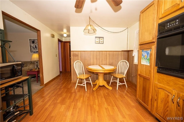 241 Shanley St, Cheektowaga, NY 14206 - dining room featuring light wood-style floors, ceiling fan, a wainscoted wall, and wood walls