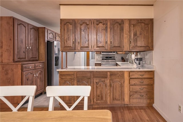22 Bugbee Rd, Oneonta-City, NY 13820 - kitchen featuring appliances with stainless steel finishes, light wood-style floors, backsplash, light countertops, and brown cabinets