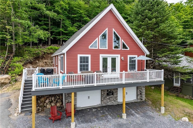 142 S Shore Rd, Webb, NY 13420 - view of front facade with stairs, french doors, a wooden deck, an attached garage, and stone siding