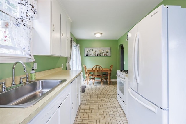 309 Brandon Rd, Irondequoit, NY 14622 - kitchen with white appliances, arched walkways, light countertops, white cabinetry, and brick patterned flooring