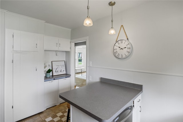 316 Walzer Rd, Irondequoit, NY 14622 - kitchen with dark countertops, white cabinets, hanging light fixtures, and a wainscoted wall