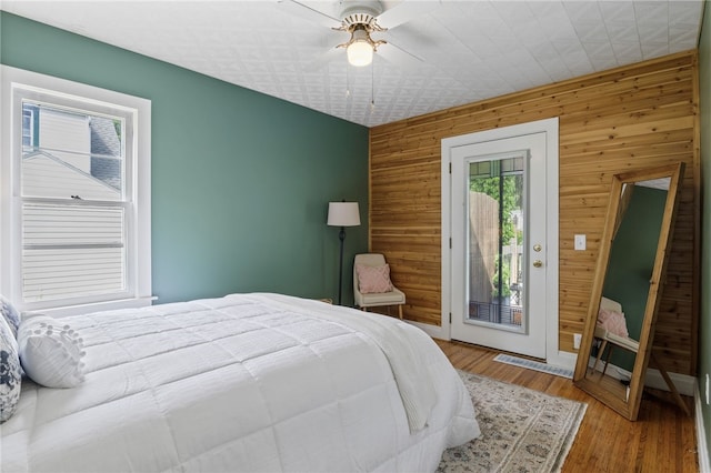 316 Walzer Rd, Irondequoit, NY 14622 - bedroom featuring wooden walls, access to outside, an accent wall, and a ceiling fan