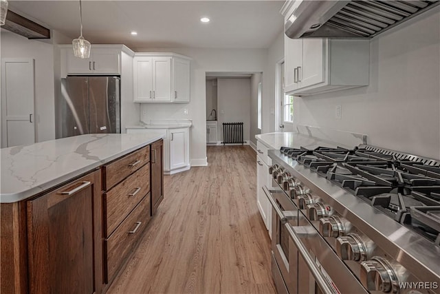 7395 W Somerset Rd, Somerset, NY 14008 - kitchen featuring wall chimney exhaust hood, stainless steel appliances, radiator, light wood-style flooring, and white cabinets