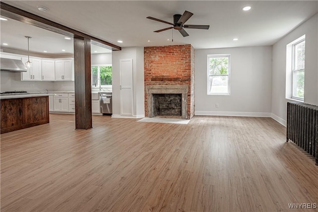 7395 W Somerset Rd, Somerset, NY 14008 - unfurnished living room featuring ceiling fan, light wood-type flooring, recessed lighting, a brick fireplace, and radiator
