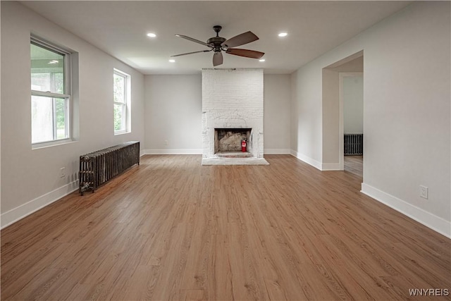 7395 W Somerset Rd, Somerset, NY 14008 - unfurnished living room featuring radiator heating unit, light wood-style floors, ceiling fan, a large fireplace, and recessed lighting