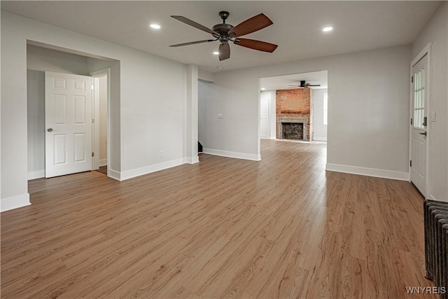 7395 W Somerset Rd, Somerset, NY 14008 - unfurnished living room featuring a ceiling fan, light wood-style floors, a brick fireplace, and recessed lighting