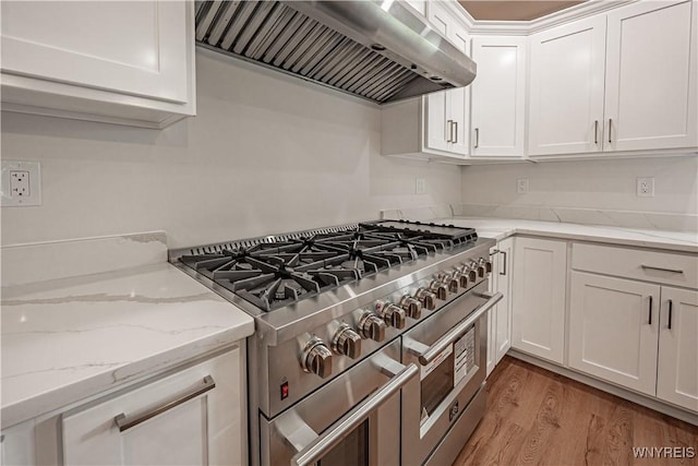 7395 W Somerset Rd, Somerset, NY 14008 - kitchen with high end stove, wall chimney range hood, white cabinetry, light wood-style floors, and light stone countertops