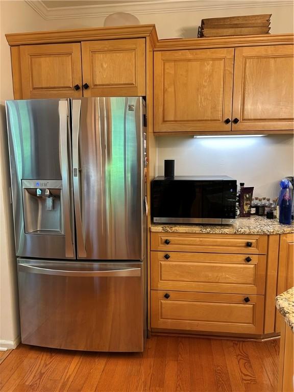 38 Hemlock Ln, Erwin, NY 14870 - kitchen with stainless steel fridge, black microwave, brown cabinetry, light wood finished floors, and light stone countertops