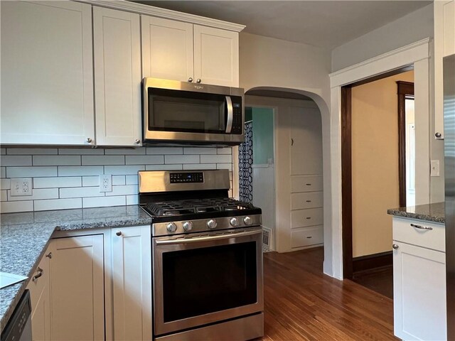 534 Mount Zoar St, Elmira-City, NY 14904 - kitchen featuring appliances with stainless steel finishes, arched walkways, dark wood-type flooring, decorative backsplash, and white cabinets