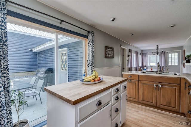 10256 State Route 26, Denmark, NY 13367 - kitchen with wood counters, a chandelier, a wainscoted wall, brown cabinetry, and a kitchen island