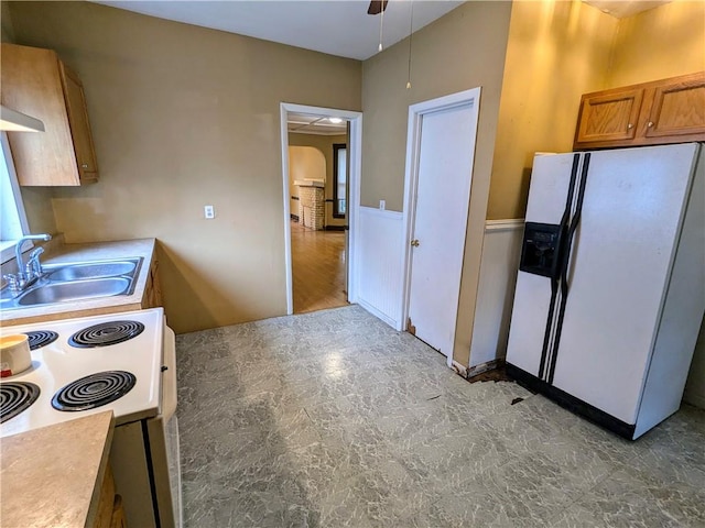 354 Euclid Ave, Elmira City, NY 14905 - kitchen with white appliances, brown cabinetry, light countertops, arched walkways, and a wainscoted wall