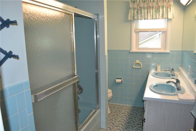 229 Everclay Dr, Greece, NY 14616 - bathroom with tile walls, double vanity, a wainscoted wall, and bath / shower combo with glass door