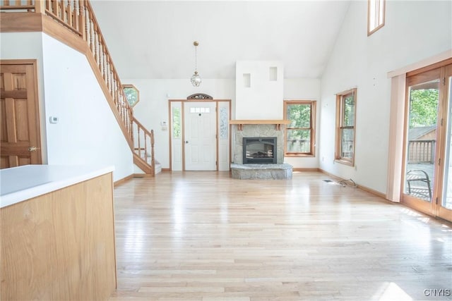 29591 Coon Bridge Rd, Theresa, NY 13691 - unfurnished living room with high vaulted ceiling, light wood-style floors, stairway, and a stone fireplace