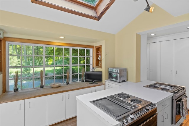 960 Landing Rd N, Brighton, NY 14625 - kitchen featuring stainless steel range with electric stovetop, healthy amount of natural light, light countertops, white cabinetry, and vaulted ceiling