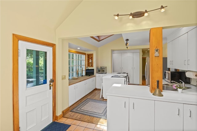 960 Landing Rd N, Brighton, NY 14625 - kitchen with stainless steel appliances, vaulted ceiling, a peninsula, white cabinets, and light countertops