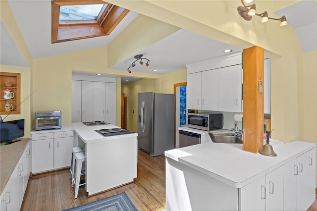 960 Landing Rd N, Brighton, NY 14625 - kitchen with stainless steel appliances, a peninsula, a skylight, light wood finished floors, and vaulted ceiling