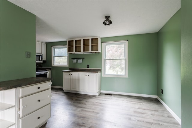 12 Rawhide Dr, Henrietta, NY 14586 - kitchen featuring stainless steel microwave, dark countertops, light wood-style flooring, and open shelves