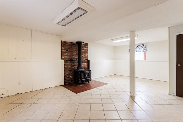 12 Rawhide Dr, Henrietta, NY 14586 - basement featuring a wood stove, light tile patterned floors, and a decorative wall