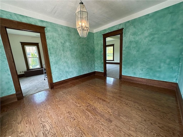 540 Derrick Rd, Foster-Town, PA 16701 - spare room featuring a chandelier, radiator heating unit, wood finished floors, and a textured ceiling