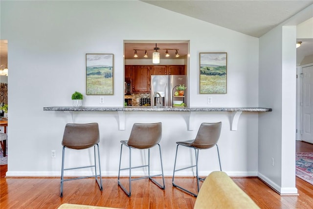 731 Brookeville Dr, Webster, NY 14580 - kitchen featuring stainless steel fridge with ice dispenser, brown cabinetry, wood finished floors, tasteful backsplash, and lofted ceiling