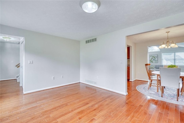 731 Brookeville Dr, Webster, NY 14580 - unfurnished living room featuring light wood-style floors, a chandelier, stairs, and a textured ceiling