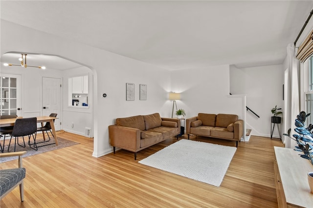 144 Montclair Dr, Irondequoit, NY 14617 - living area with arched walkways, light wood-style floors, and a chandelier