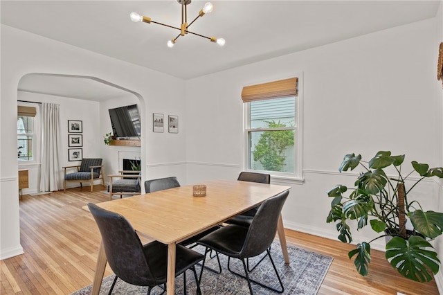 144 Montclair Dr, Irondequoit, NY 14617 - dining space with a fireplace, a chandelier, plenty of natural light, and light wood-style flooring