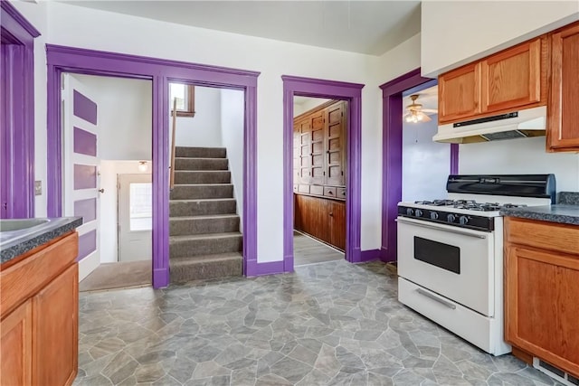 4618 Oak Orchard Rd, Barre, NY 14411 - kitchen with gas range gas stove, under cabinet range hood, stone floors, dark countertops, and a ceiling fan