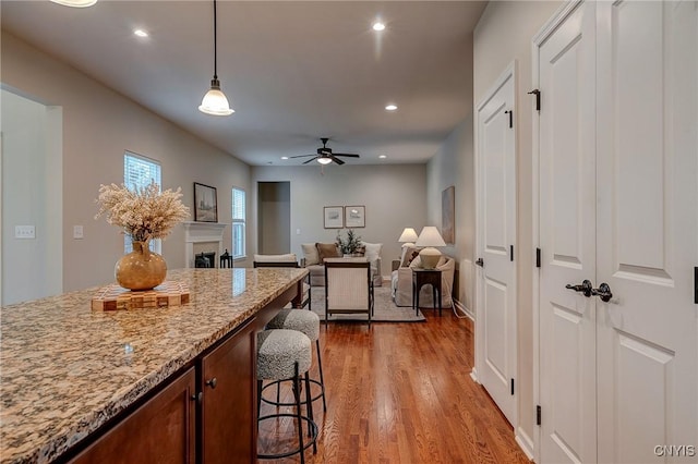 8497 Melo Cir, Clay, NY 13041 - kitchen featuring a kitchen breakfast bar, wood finished floors, hanging light fixtures, ceiling fan, and recessed lighting