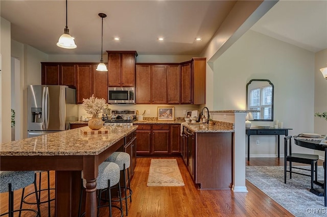 8497 Melo Cir, Clay, NY 13041 - kitchen featuring stainless steel appliances, wood finished floors, a kitchen breakfast bar, light stone counters, and recessed lighting