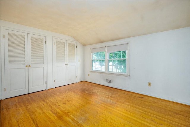 170 Kings S, Irondequoit, NY 14617 - unfurnished bedroom featuring two closets, vaulted ceiling, and light wood-style flooring