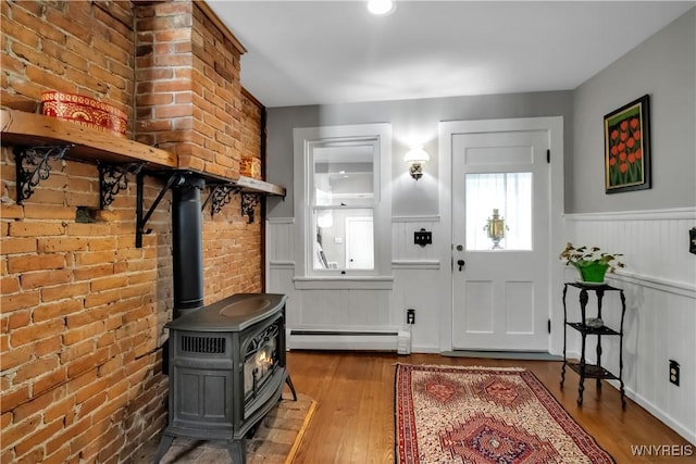 2565 Bowen Rd, Elma, NY 14059 - entryway featuring a baseboard radiator, a wainscoted wall, wood finished floors, a wood stove, and brick wall